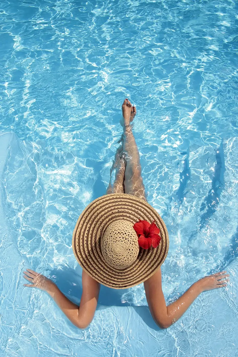 woman in hat relaxing by pool